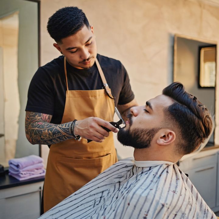 Barbier qui taille la barbe d'un client